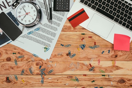 top view of newspaper, laptop, credit card, smartphone and office supplies on table