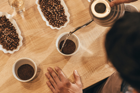 overhead view of man pouring hot water into bowl with grind coffeeの写真素材