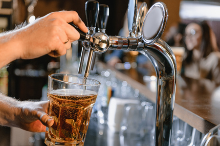 cropped image of barman pouring beer in glass at bar