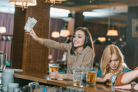 beautiful girl with money paying for drink at barの写真素材