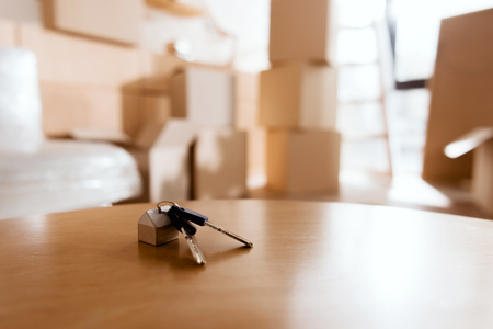 selective focus of keys on table in new house with cardboard boxes, moving conceptの写真素材