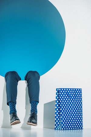 cropped shot of young man with shopping bag falling into hole on greyの写真素材