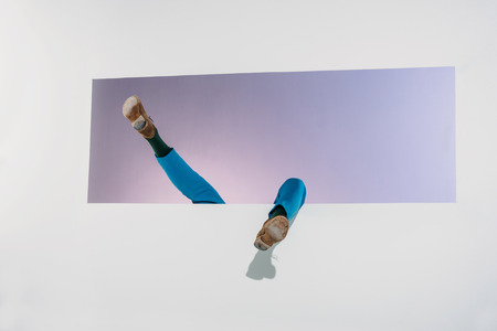 cropped shot of man falling into aperture on grey