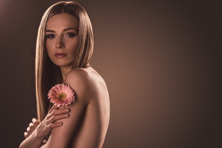 beautiful girl holding gerbera flower, on brown with copy spaceの写真素材