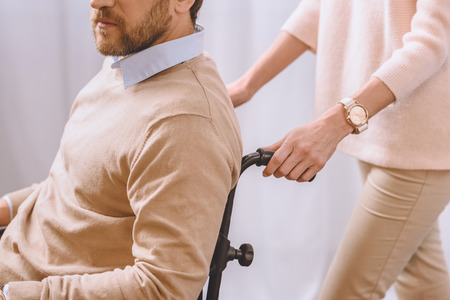 cropped image of wife carrying husband in wheelchairの写真素材