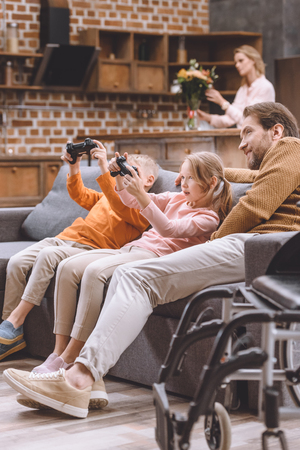 happy father looking how children playing video gameの写真素材