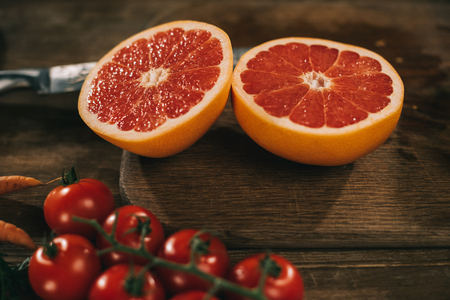 cut grapefruit on wooden board and cherry tomatoes on tableの写真素材