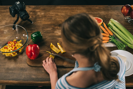 overhead view of female food blogger cutting bell peppersの写真素材