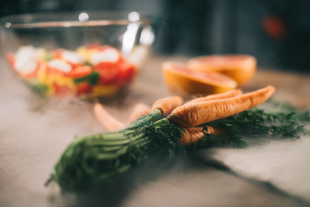ripe carrots on wooden table with vegetables on blurred backgroundの写真素材