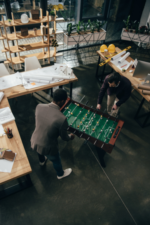 high angle view of multiethnic architects playing table football in officeの写真素材