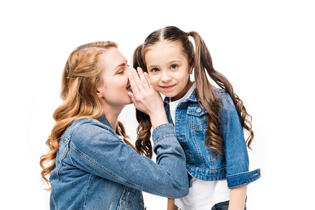 mother telling secret to little daughter isolated on white