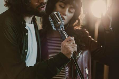 close-up shot of young couple performing song with vintage microphoneの写真素材