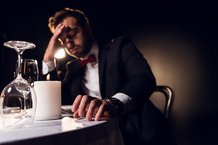 handsome upset man waiting for romantic date in restaurantの写真素材