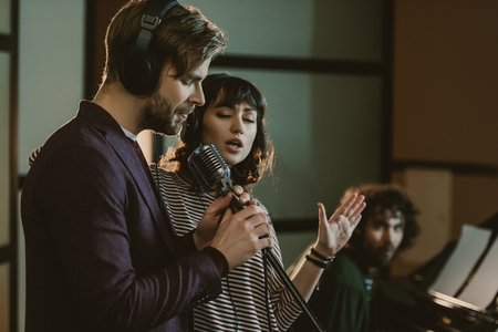 singers performing song while man playing piano behindの写真素材