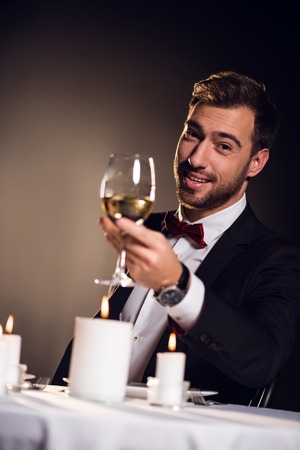 happy bearded man with glass of wine sitting in restaurantの写真素材