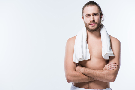 Cheerful caucasian man with bath towel around his neck looking at camera with arms crossed, isolated on whiteの写真素材