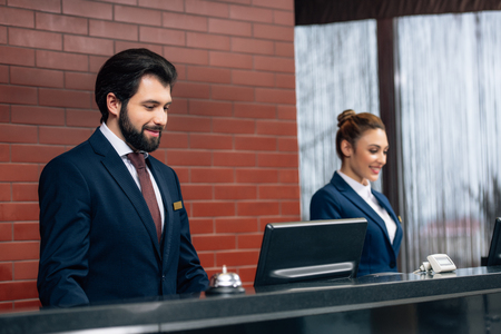 hotel receptionists working with computers together at counterの写真素材