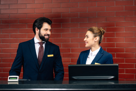 hotel receptionists looking at each other by counterの写真素材