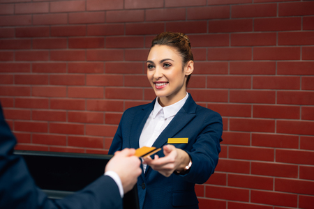 young beautiful hotel receptionist taking credit card from customerの写真素材