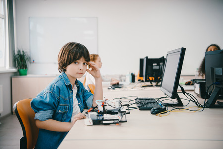 teen kid looking at camera while programming diy robot at machinery classの写真素材