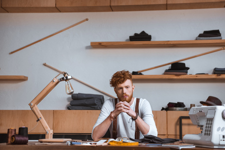 stylish young male fashion designer sitting at table at workplaceの写真素材