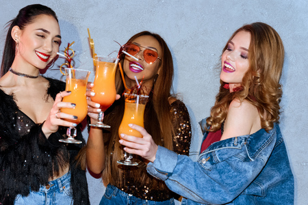 beautiful smiling multiethnic girls clinking glasses at partyの写真素材