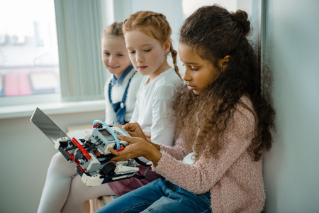 group of little schoolgirls working with laptop together on stem education class