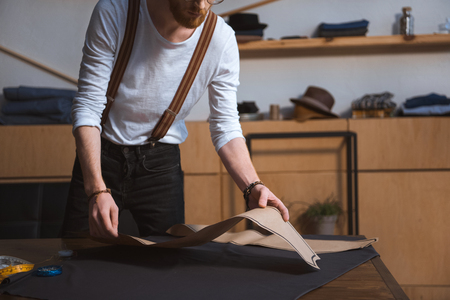 cropped shot of young male fashion designer working with sewing patterns and fabric