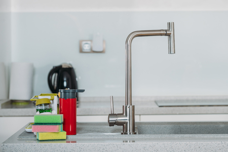 dishwashing sponges near water tap in kitchenの写真素材