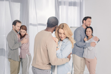 three multiethnic couples hugging during psychotherapyの写真素材