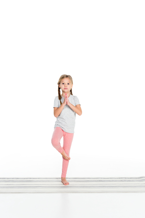 kid practicing yoga on yoga mat isolated on whiteの写真素材