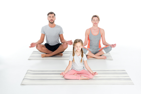 athletic family practicing yoga on mats together isolated on whiteの写真素材