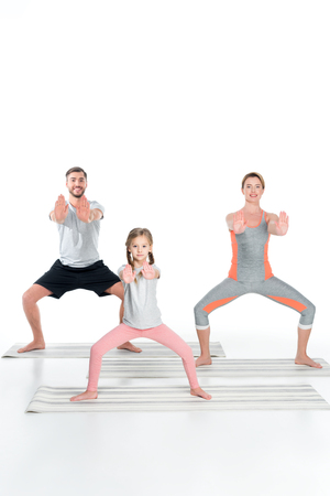 athletic family practicing yoga on mats together isolated on whiteの写真素材