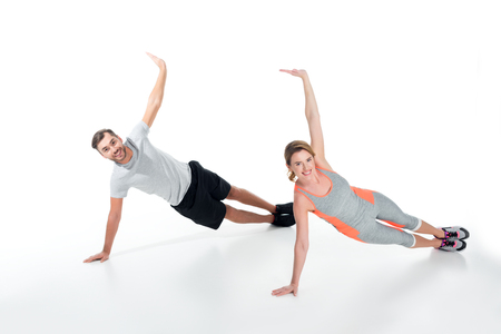 smiling sportive couple exercising together isolated on whiteの写真素材