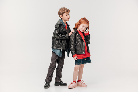jealous little boy listening while his girl talking by phone isolated on greyの写真素材