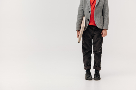 cropped shot of stylish little schoolboy with big book isolated on greyの写真素材