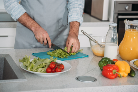 cropped image of man cutting vegetablesの写真素材