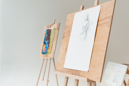 easels with artistic paintings in empty art studio on greyの写真素材