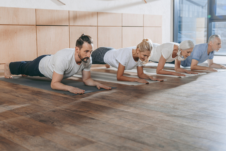 group of people doing plank on yoga mats in studioの写真素材