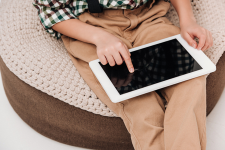 cropped shot of little boy sitting and using digital tablet with blank screen on greyの写真素材