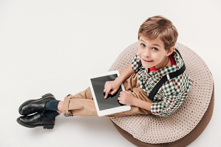 high angle view of little boy using digital tablet and looking at camera isolated on greyの写真素材
