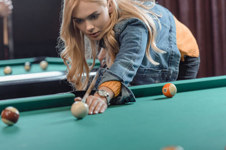 young beautiful caucasian woman playing in pool at bar