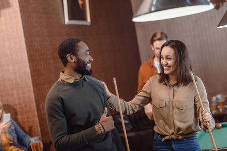 man and woman looking at each other in pool bar with friendsの写真素材