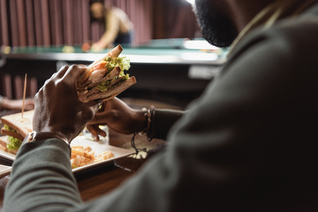 cropped image of african amercian man eating sandwich at barの写真素材