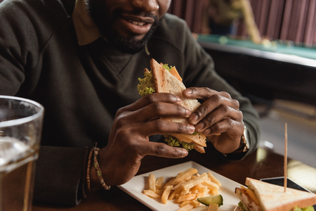cropped image of african amercian man eating sandwich at barの写真素材
