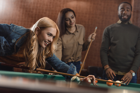 young successful multiethnic friends playing in pool at barの写真素材