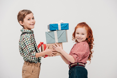 cute little children holding gift boxes and smiling at camera isolated on greyの写真素材