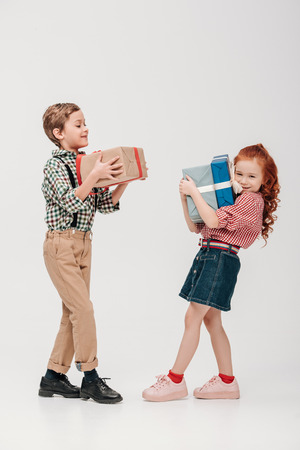 adorable little kids holding colorful gift boxes isolated on greyの写真素材