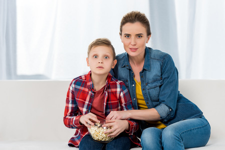 interested mother and son watching movie together with popcornの写真素材