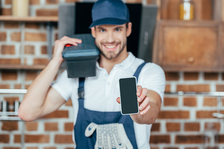 smiling young home master holding smartphone with blank screenの写真素材